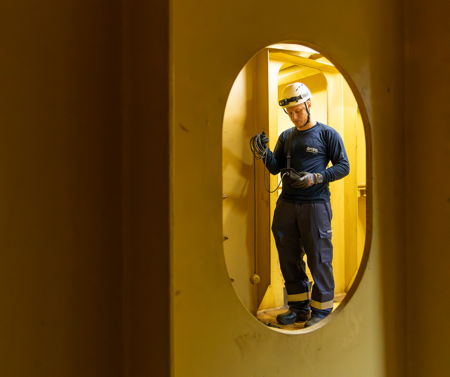 Un employé d'Arizo mesure l'atmosphère dans un espace confiné à bord d'un navire.